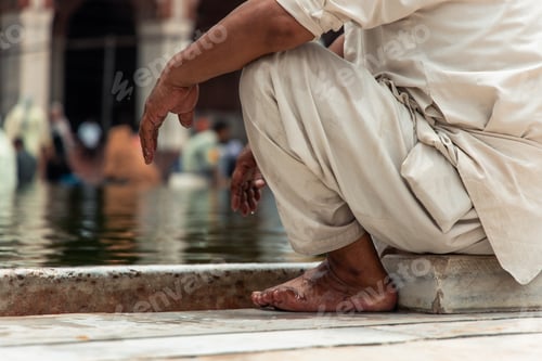 Preview: Indian man resting by the water in Jama Masjid Mosque in Delhi, India