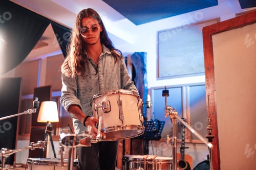 Preview: Drummer setting up a tom onto his drum set in a music studio.