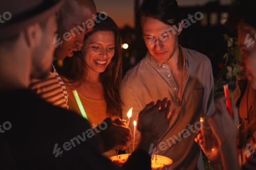 Preview: Friends on a rooftop lighting candles on a birthday cake