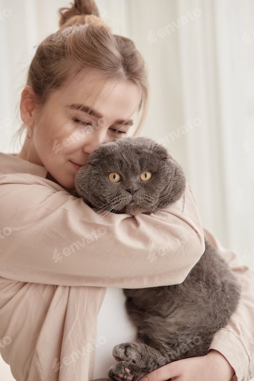Preview: Beautiful woman hugs her cat. Warm, cozy home concept. Lifestyle photography.