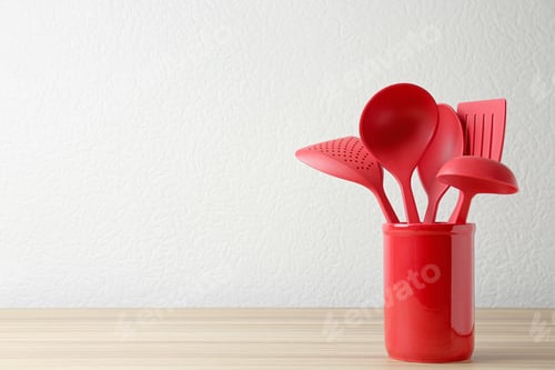 Preview: Set of kitchen utensils in stand on wooden table near light wall. Space for text