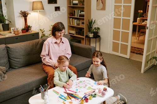 Preview: Granny Supervising Two Girls Drawing Indoors