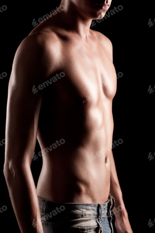 Preview: Young athletic man with naked torso in jeans standing over black background