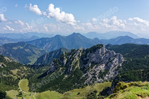Preview: Panoramic view of lush green mountains under clear sky.