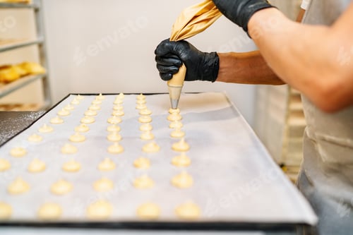 Preview: hands of a Pastry Chef with confectionary bag squeezing cream in the pastry shop bakery