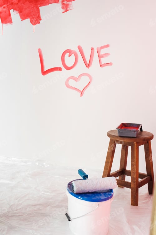 Preview: wall with lettering love and heart symbol, paint tin with paint roller and chair with roller tray