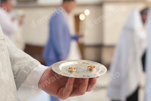 Preview: Close-up photo of a wedding ring held by a priest in a church before the wedding ceremony