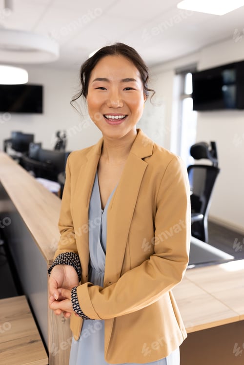 Preview: Vertical image of happy asian businesswoman looking at camera in office