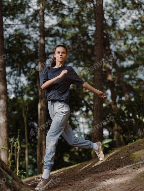 Preview: Energetic young woman jogging in forest, wearing casual athletic outfit, showing determination and
