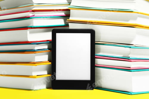Preview: Modern e-book reader and stacks of hard cover books on yellow background, closeup