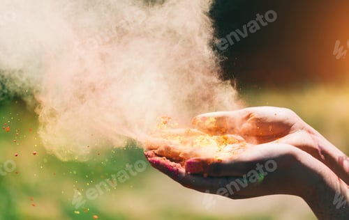Preview: Holi powder held in woman's hand and a cloud of dust