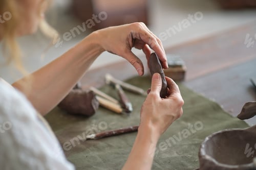 Preview: Potter female kneads a piece of clay with her hands in her Studio workshop