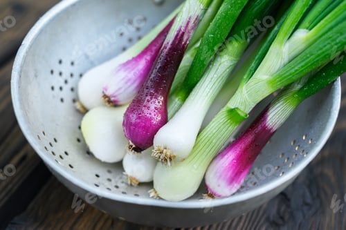 Visualização: Spring onions in metal bowl on dark wooden surface