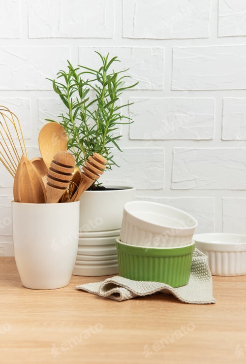 Preview: Kitchen utensils, rosemary plant, and ramekins creating a cozy culinary scene