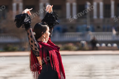 Preview: Woman in flamenco outfit raising arms while dancing outdoors
