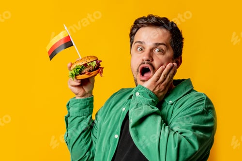 Preview: Surprised man with burger and german flag on yellow background