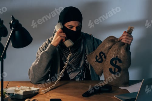 Preview: Terrorist in mask holding bags with money and talking on phone in room