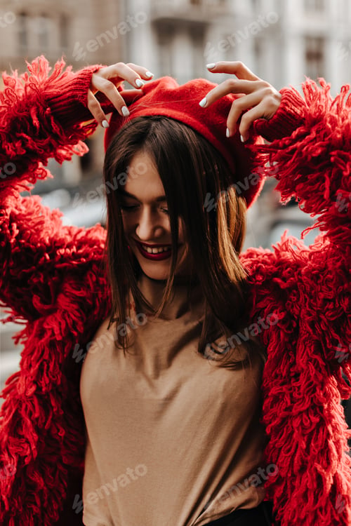 Preview: Portrait of charming woman with red lips, dressed in red eco-coat and beret. Lady in great mood wal
