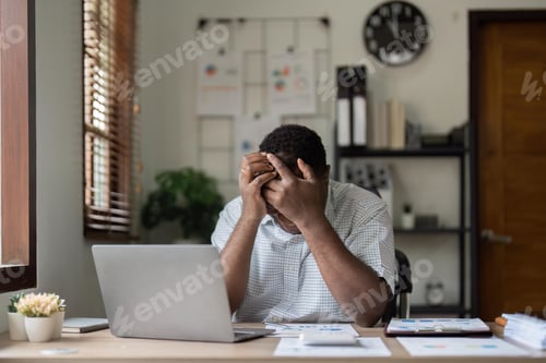 Preview: Unhappy hopeless African American man holding head in hands, overwhelmed tired businessman sitting