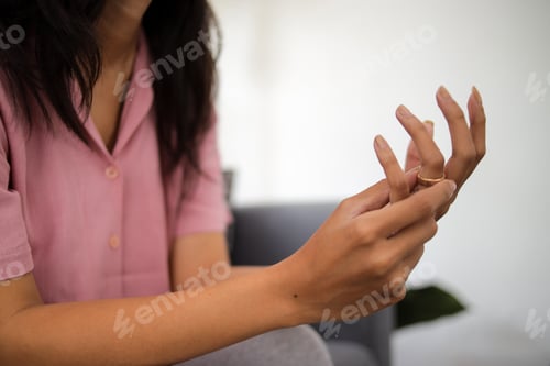 Preview: Close-up Woman Taking Off Wedding Ring Indoors. Divorce Concept.