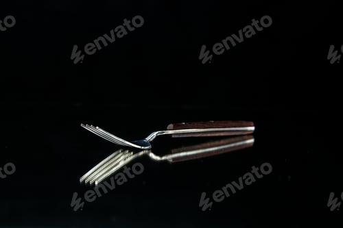 Preview: Elegant shiny metal fork on black background with free space in close up view