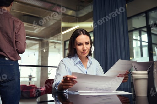 Preview: Focused female employee dealing with paperwork in company office