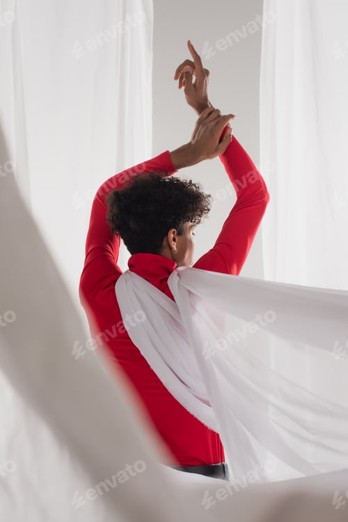 Preview: back view of african american man with trendy hairstyle posing near white cloth with raised hands