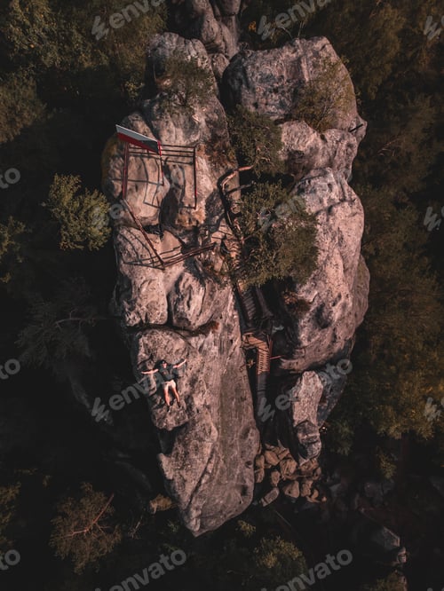 Preview: Aerial top view of a man lying on top of a rocky hill