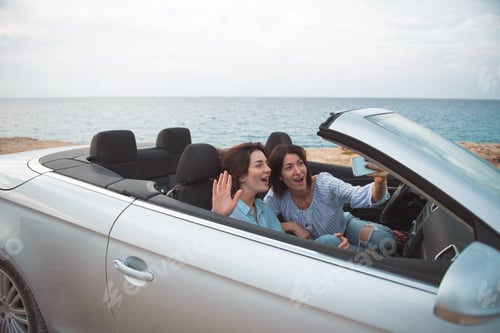 Preview: Selfie Time. Young Delighted Women Are Sitting In Cabriolet With Open Roof And Taking Picture While