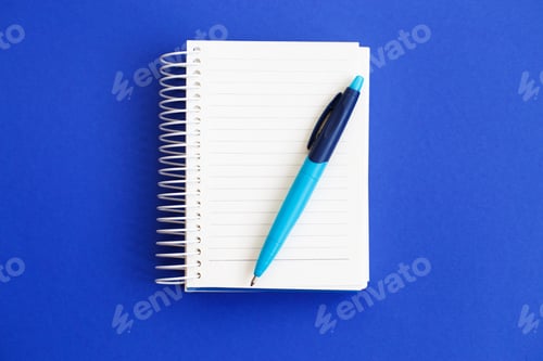 Preview: Top view of blank note paper with pen on blue background.