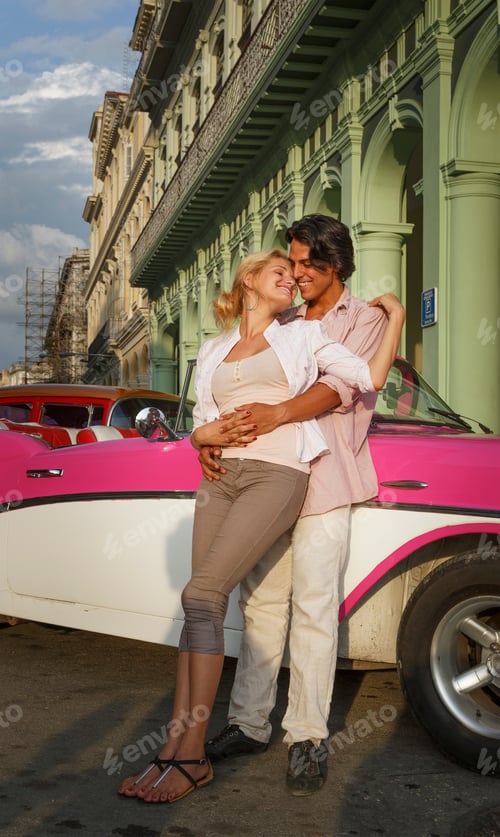 Preview: Young couple leaning against vintage convertible, Havana, Cuba