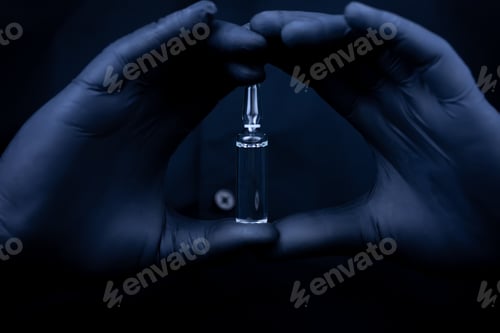Preview: the hands of a medical worker in black medical gloves hold showing a closed ampoule with a vaccine