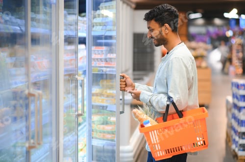 Preview: Portrait of handsome young Indian man standing at grocery shop or supermarket. Selective Focus.