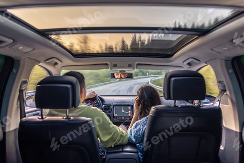 Preview: Rear back view from passenger seat of man and lady sitting inside car.