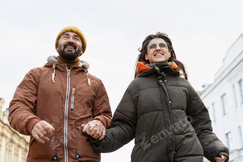 Preview: Happy couple holding hands and walking in the city during winter