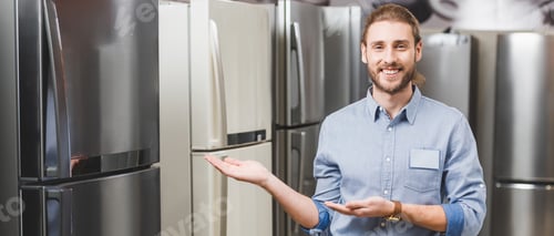 Preview: panoramic shot of smiling consultant pointing with hands at fridge in home appliance store
