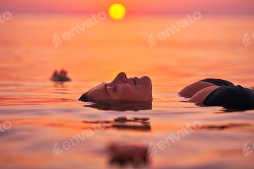 Preview: Young woman swimming in the sea on sunrise