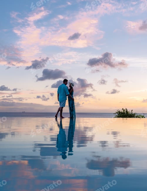 Preview: Young men and women watching sunset with reflection in the infinity pool at Saint Lucia Caribean