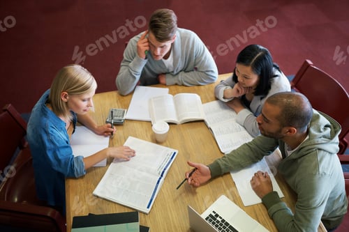 Preview: Cramming some last minute knowledge. A group of young people studying together in the library.