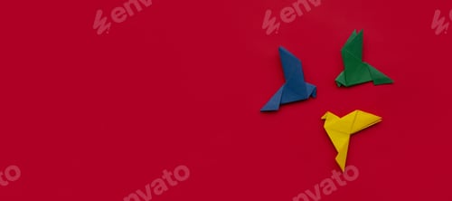 Preview: three paper origami pigeons yellow, green and blue on red background