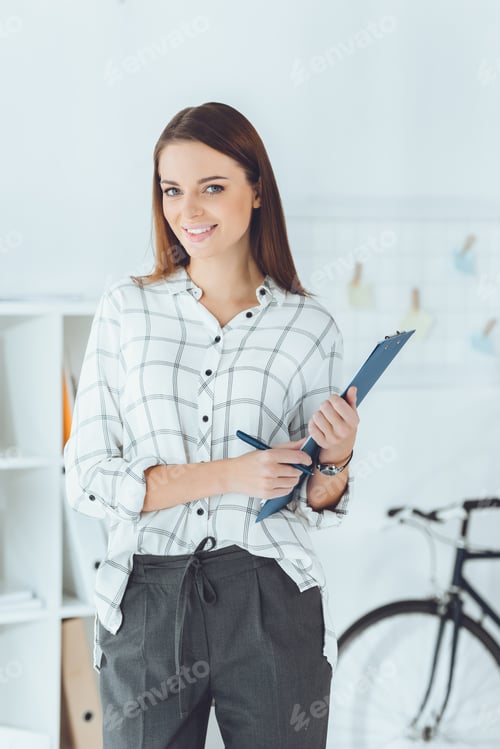 Smiling Woman Holding a Clipboard in an Office