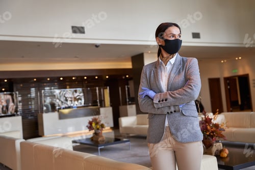 Preview: Hotel owner standing with her arms crossed in the hall