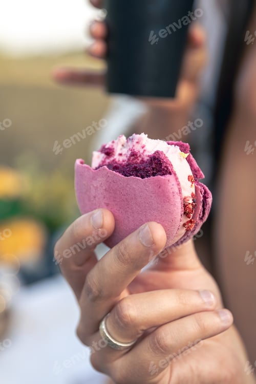 Preview: Pink macaron dessert in a man's hand, close-up.