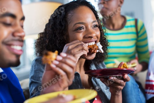 Preview: Three adult friends eating takeaway on living room sofa