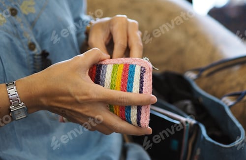 Preview: Woman holding colors wallet in hand while sitting with blur blur purse background