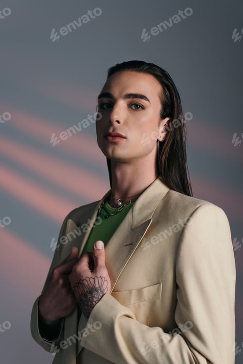 Preview: Portrait of brunette queer person in jacket standing on abstract background