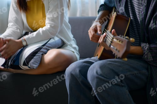 Preview: Happy Asian woman enjoying music with headphones while man plays guitar and harmonica