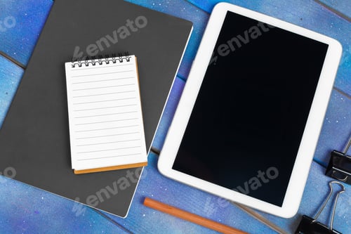 Preview: Workplace with blank digital tablet, paper on blue wooden work table. Above view shot