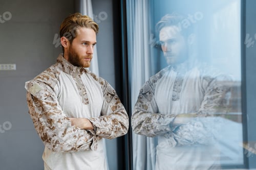 Preview: Masculine confident military man standing and looking out window indoors