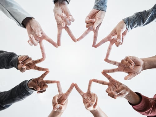 Preview: Below hands in circle making a star shape. A group of people putting their fingers together while s